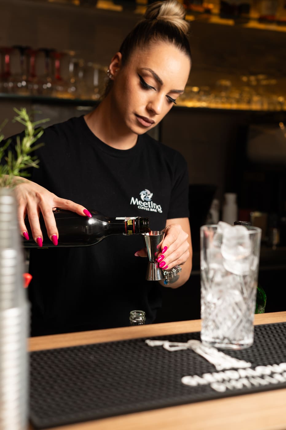 Barista del Meeting Coffee Bar che versa da una bottiglia al bancone