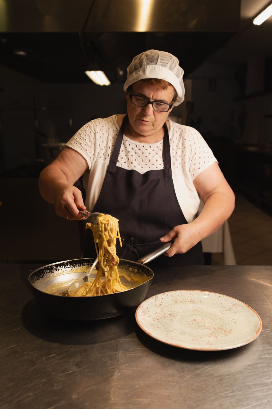 Cuoca che impiatta un primo nella cucina di Tenuta Uliveto